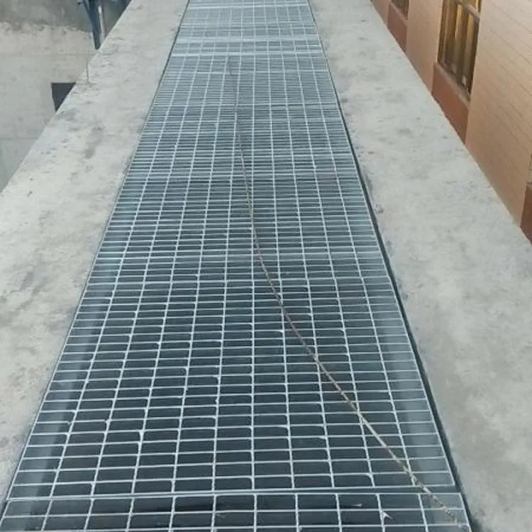 Steel grating walkway platform with handrails beside factory buildings; eye-level frontal view