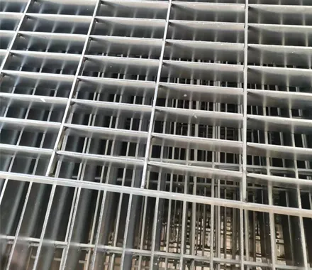 Weathered welded grating installed as industrial stair landing/platform at construction site; ground-level view