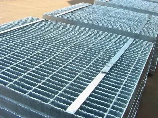 Stacks of galvanized serrated welded grating panels bundled with metal strapping in staging yard
