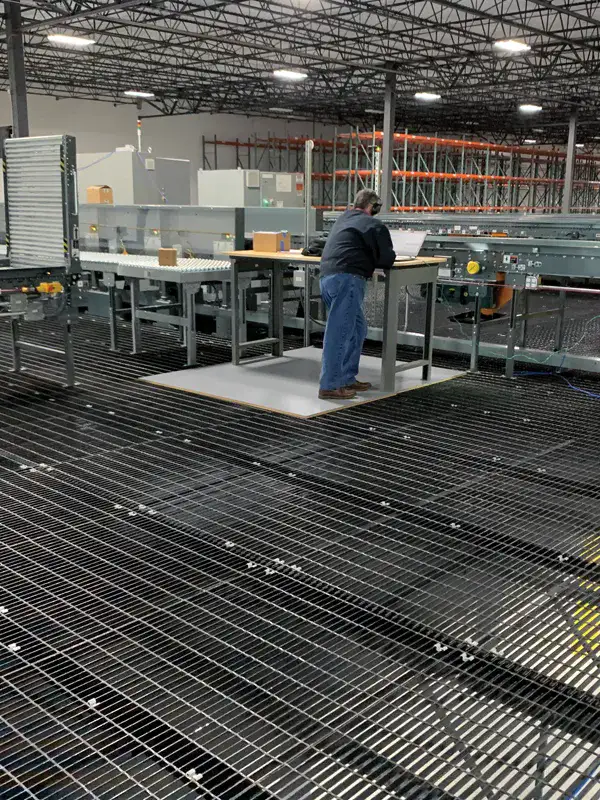 Grating panels installed as mezzanine floor decking inside warehouse; seen from below