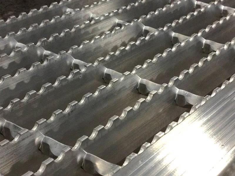 Serrated steel grating close-up showing saw-tooth anti-slip bearing bar edges; diagonal composition