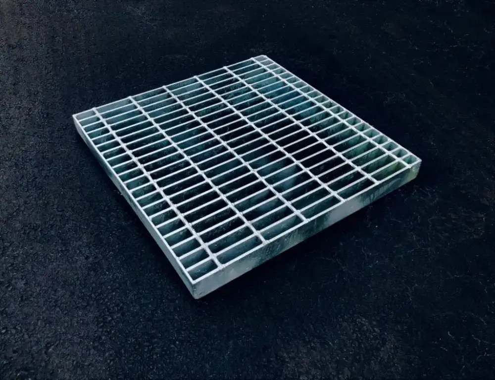 Galvanized welded grating panels stacked in warehouse; front three-quarter view