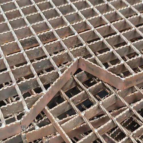 Close-up of serrated welded grating panels and shaped stair tread blanks; high-angle diagonal stack